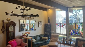 A cozy living room with a wooden ceiling, a green sofa, a pink armchair, a wooden coffee table, and a decorative mirror. - Charming 3-bedroom house in Pleasant Hinsdale with WiFi (Hinsdale)