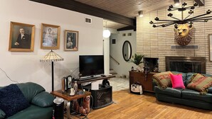 A living room with a fireplace, a television, and a green sofa. - Charming 3-bedroom house in Pleasant Hinsdale with WiFi (Hinsdale)