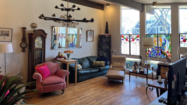 A living room with a wooden ceiling, a chandelier, a large window with stained glass, a sofa, a chair, and a desk with a computer. - Charming 3-bedroom house in Pleasant Hinsdale with WiFi (Hinsdale)