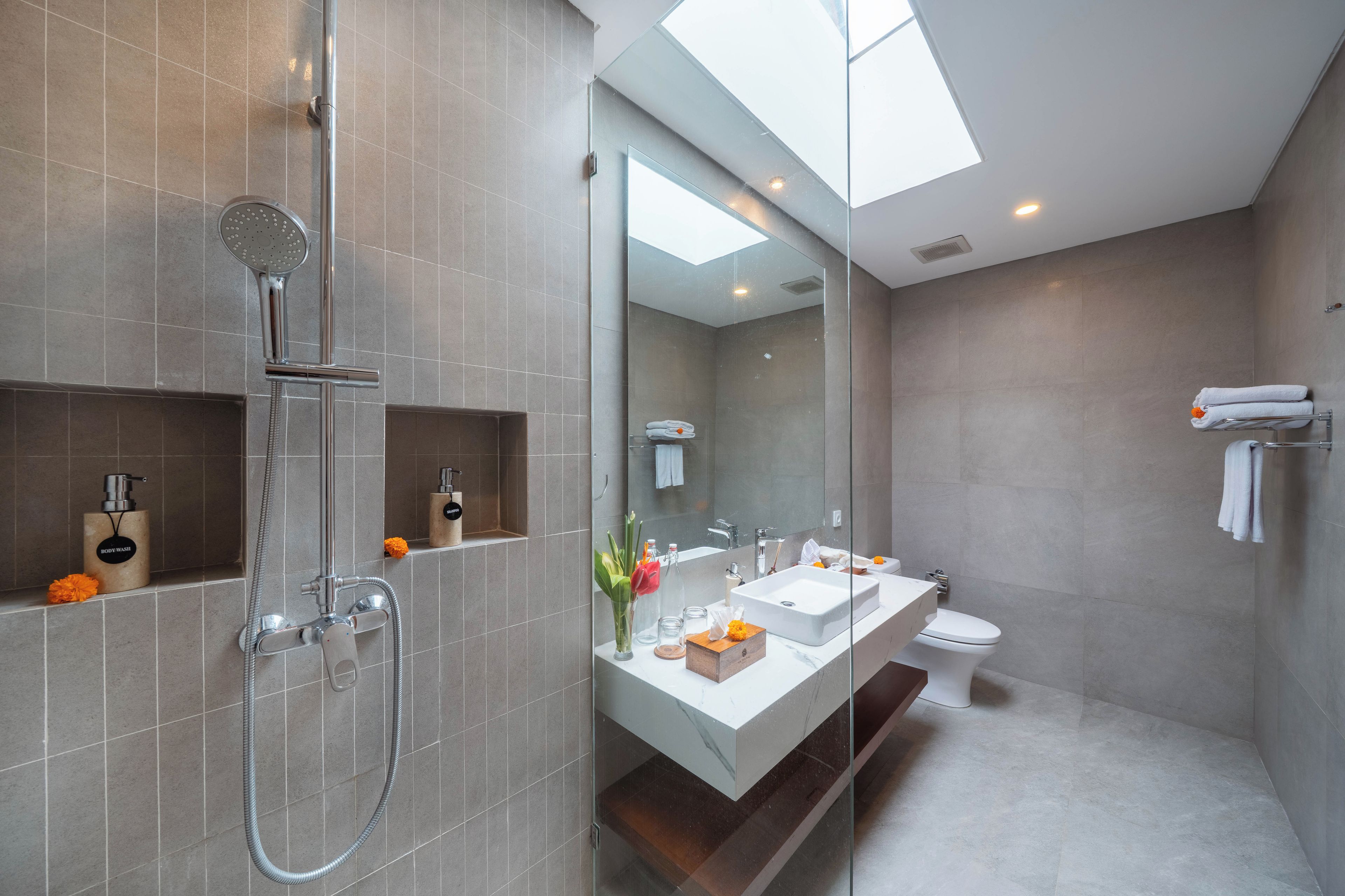 A modern bathroom with a glass-enclosed shower, a vanity with a mirror, and a toilet.