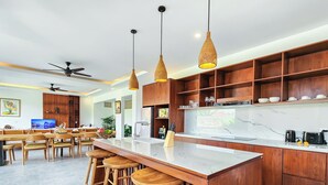 A modern kitchen with wooden cabinetry, a marble countertop, and a bar area with stools.