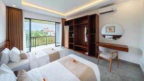 A hotel room with two beds, a desk, a wardrobe, and a balcony with a view.