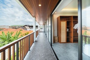 A balcony with a view of construction sites, a wooden ceiling, and a glass door leading to a room with a built-in wardrobe.