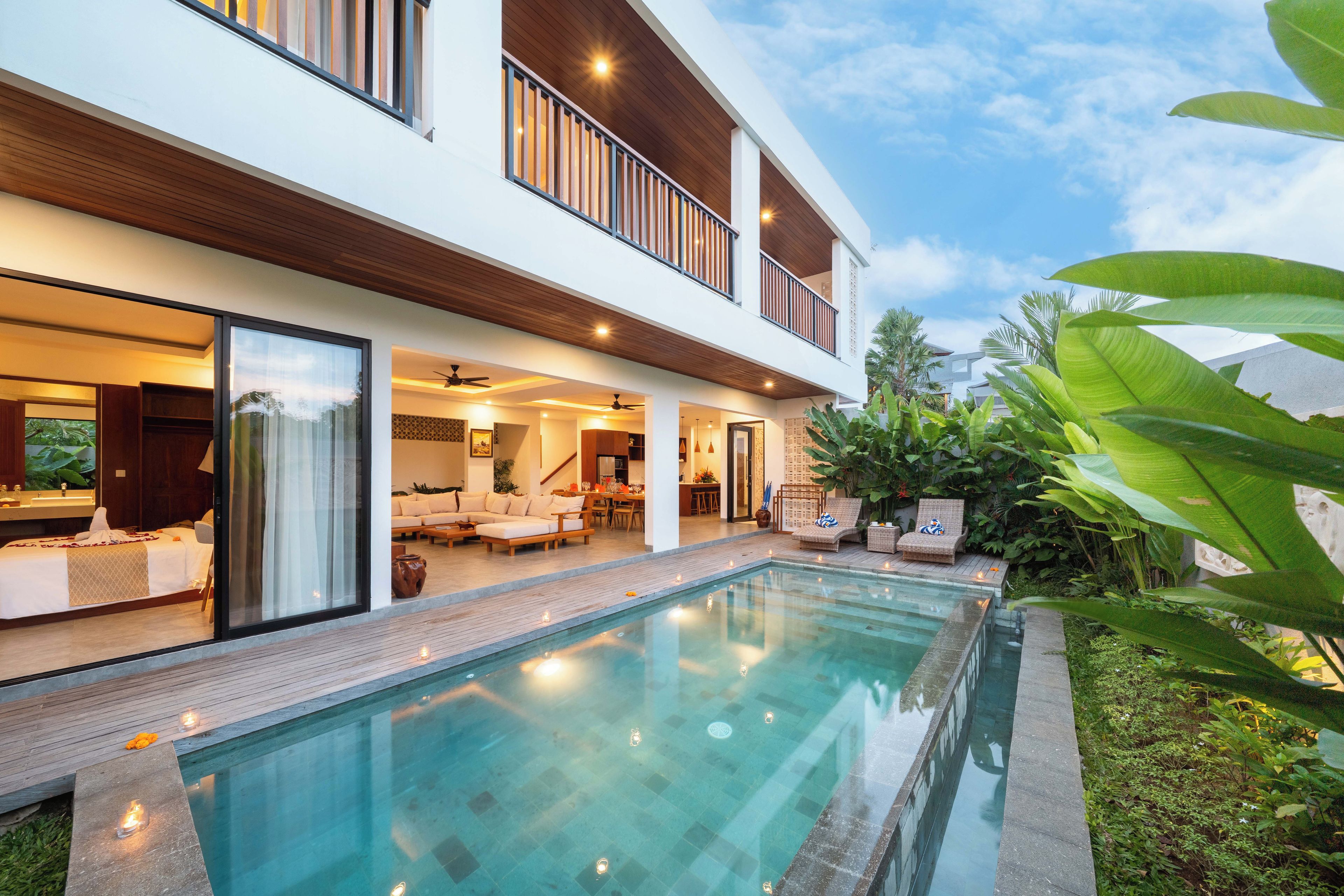 A modern two-story house with a swimming pool, outdoor seating, and lush greenery.