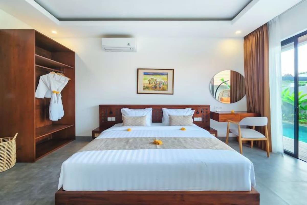 Habitación de hotel con una cama grande, un armario de madera, un escritorio y vistas al exterior.