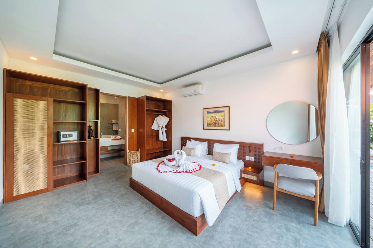 Ein geräumiges Hotelzimmer mit einem großen Bett, einem Holzschrank, einem Badezimmer und einer Sitzecke.
