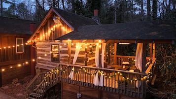 A log cabin with a porch, string lights, and a staircase.