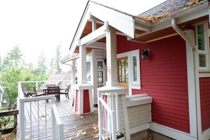 Ein rotes Haus mit weißer Veranda und einer Holzterrasse.