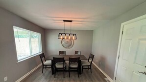 A dining area with a rectangular table, six chairs, a decorative wall piece, and a ceiling light fixture. - 2 King Bedroom Ranch - Hot Tub -Pets and Kids Welcome - Fenced Yard - Smart TV (Gahanna)