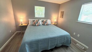 A bedroom with a bed, two bedside tables, a window, and a wall-mounted light fixture. - 2 King Bedroom Ranch - Hot Tub -Pets and Kids Welcome - Fenced Yard - Smart TV (Gahanna)