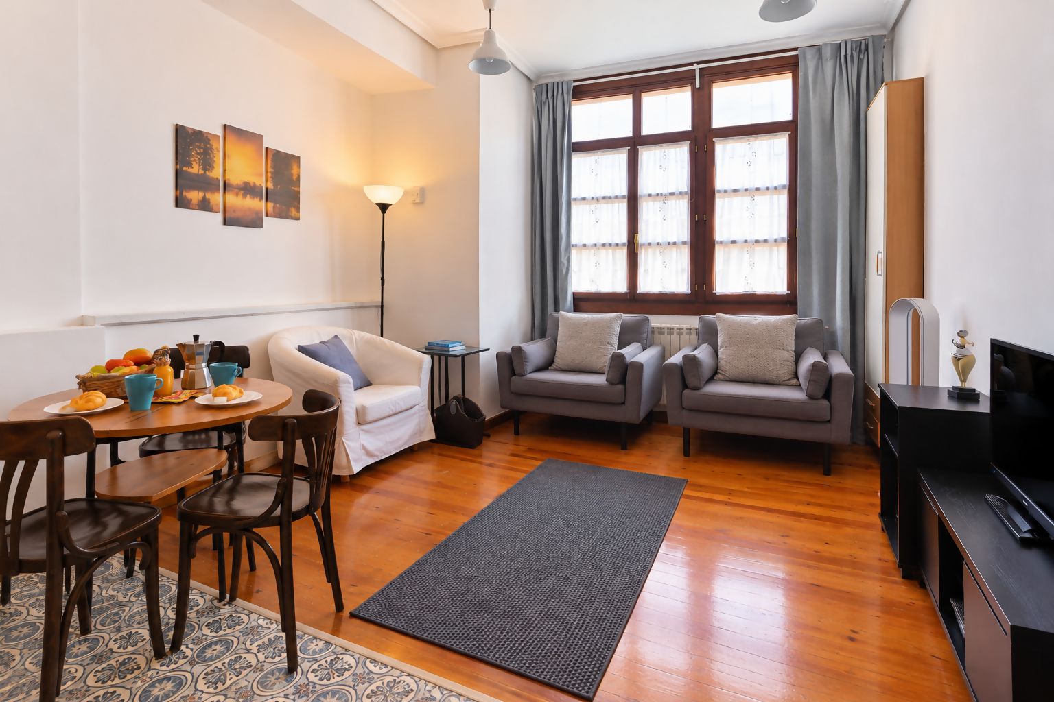 Una sala de estar amoblada con comedor, sofá, mesa de centro y televisión.