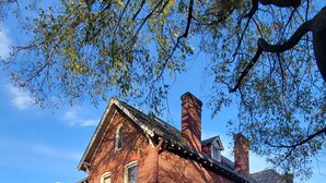 A red brick building with a central staircase and a small front porch.