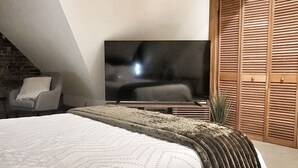 A bedroom with a large bed, a television, and a wooden wardrobe.