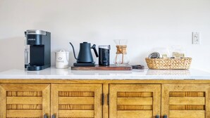 A kitchen counter with a Keurig coffee maker, a coffee pot, a glass carafe, and a basket of coffee pods. - Peaceful Apartment with Waterview and Patio, Walk to Beach! (New Haven)