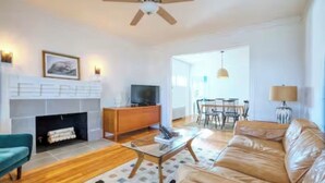 A modern living room with a fireplace, leather sofa, and a dining area. - Peaceful Apartment with Waterview and Patio, Walk to Beach! (New Haven)