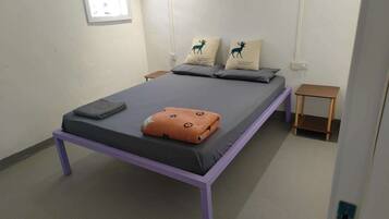 A single bed with a purple frame, grey bedding, and two pillows with deer designs.
