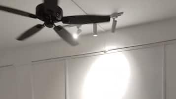 A bedroom with a bed, a ceiling fan, and a bedside table.