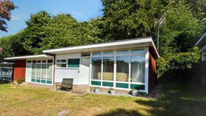 A two-story house with a garage, a front porch, and a small garden area. - Chalet 72 is an elevated, single storey chalet on Kings Chalet Park, Cromer, in easy reach of Cromer (Cromer)