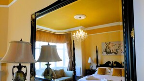 A hotel room with a large ornate mirror, a chandelier, a bed with white linens, and a decorative lamp. - Little Manor House boasts grand rooms and tall ceilings in this imposing Victorian House in the hear (Cromer)