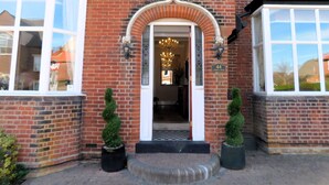 A brick building with a white entrance, a number '44' sign, and two potted plants. - Little Manor House boasts grand rooms and tall ceilings in this imposing Victorian House in the hear (Cromer)
