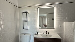 Ein Badezimmer mit Toilette, Waschbecken mit Spiegel und Handtuchhalter.