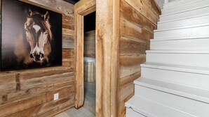 Interior de madera con un cuadro enmarco de un caballo, una puerta blanca y una pared exterior blanca.