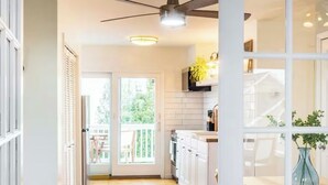 Une cuisine moderne avec des armoires blanches, un plan de travail en bois et un ventilateur de plafond.
