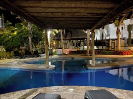 Una piscina al aire libre, sombrillas, sillones reclinables de piscina