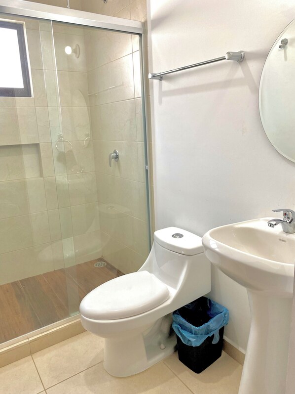 A bathroom with a toilet, a sink, and a glass shower enclosure.
