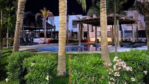 A pool area with palm trees and a building in the background. - Palmilla Sunscape  (Mazatlán)