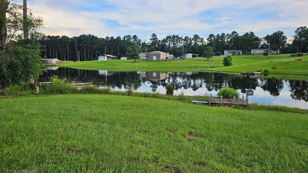 A serene lakeside property with a private dock, a small building, and a grassy area.