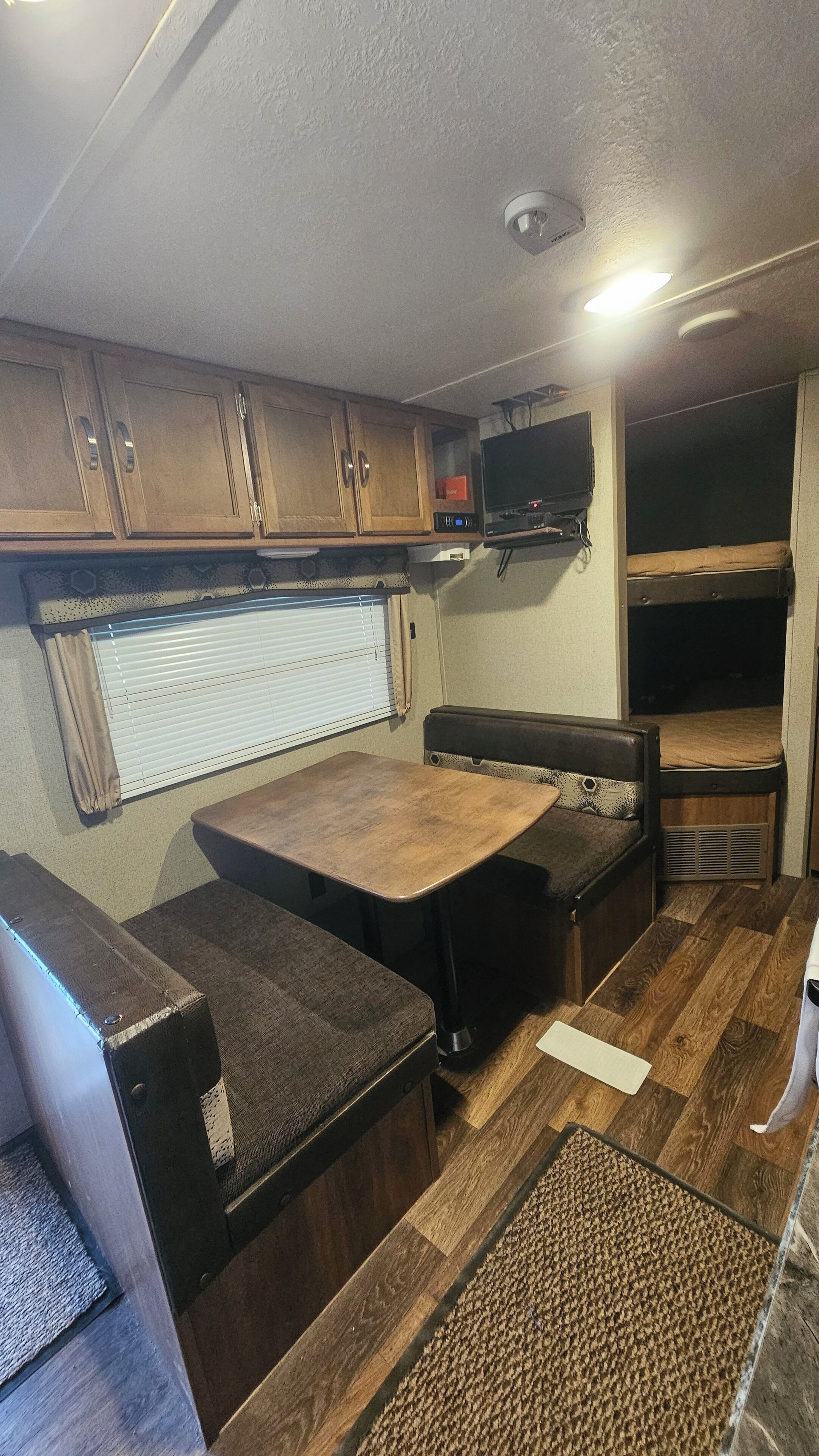 A compact RV interior with a kitchenette, a dining area, and a sleeping space.