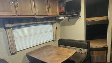 A compact RV interior with a kitchenette, a dining area, and a sleeping space.