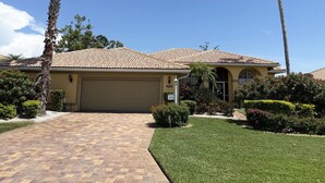 A residential house with a tiled roof, a garage, and a well-maintained lawn. - Golf & Gulf – Pool Home Near Beach w/ Cart (Englewood)