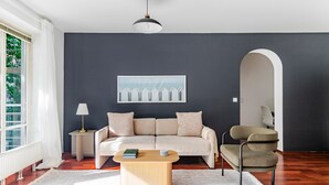 A modern living room with a dark wall, a beige sofa, a wooden coffee table, a lamp, and a chair.