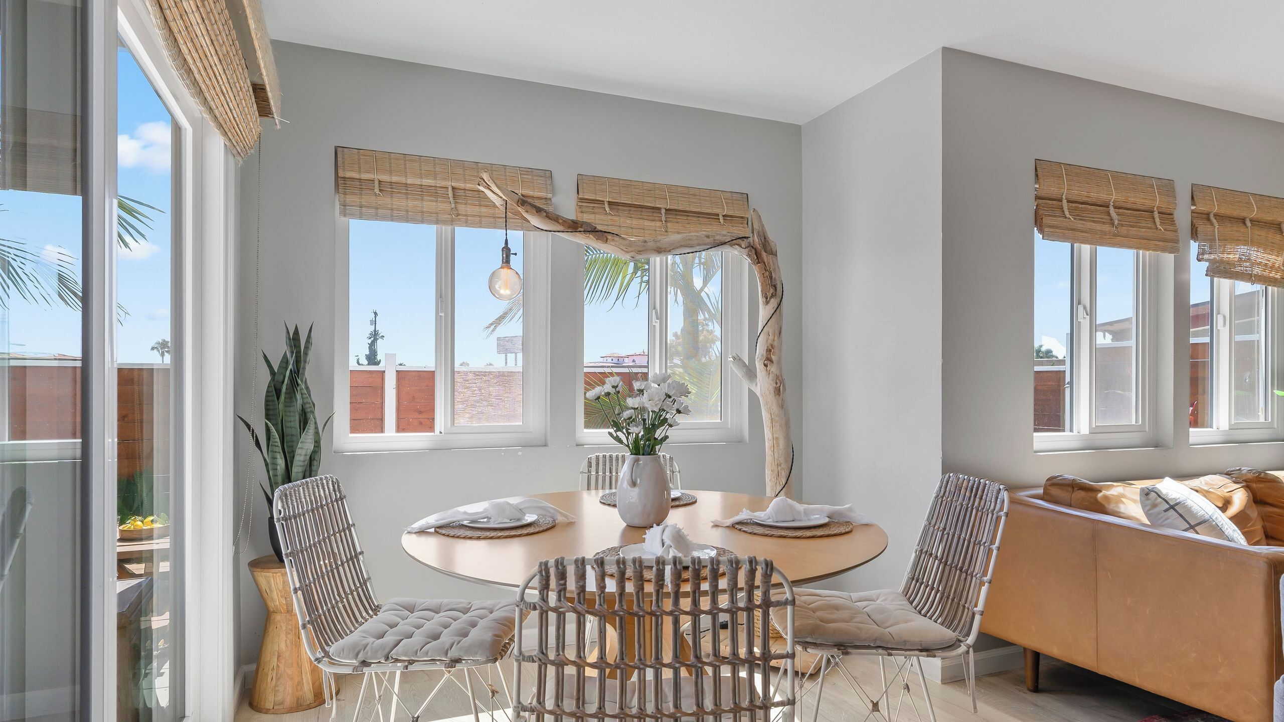 A dining area with a round table, chairs, and a vase of flowers.
