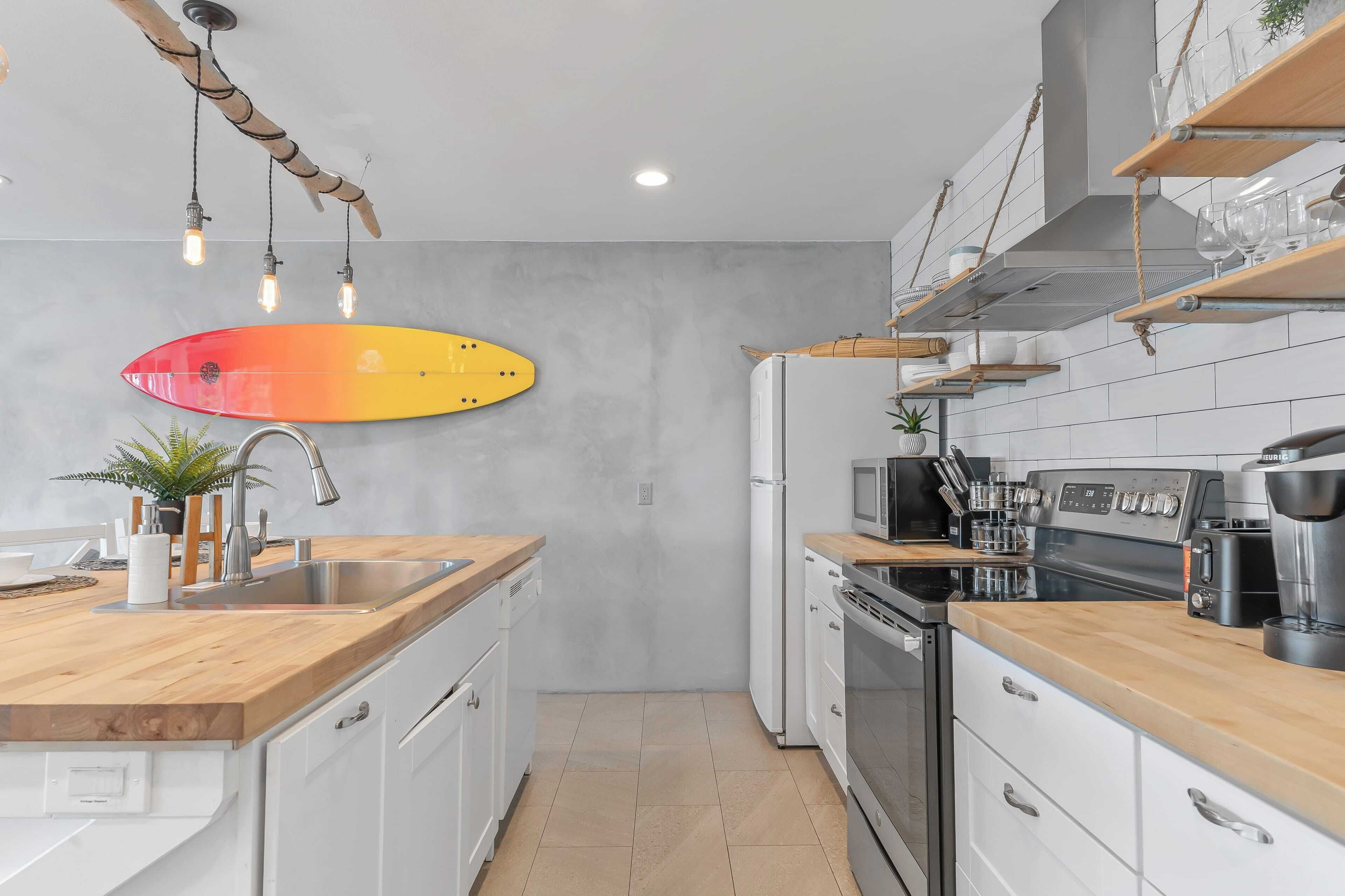 Una cocina moderna con encimera de madera, armarios blancos, horno empotrado y microondas.