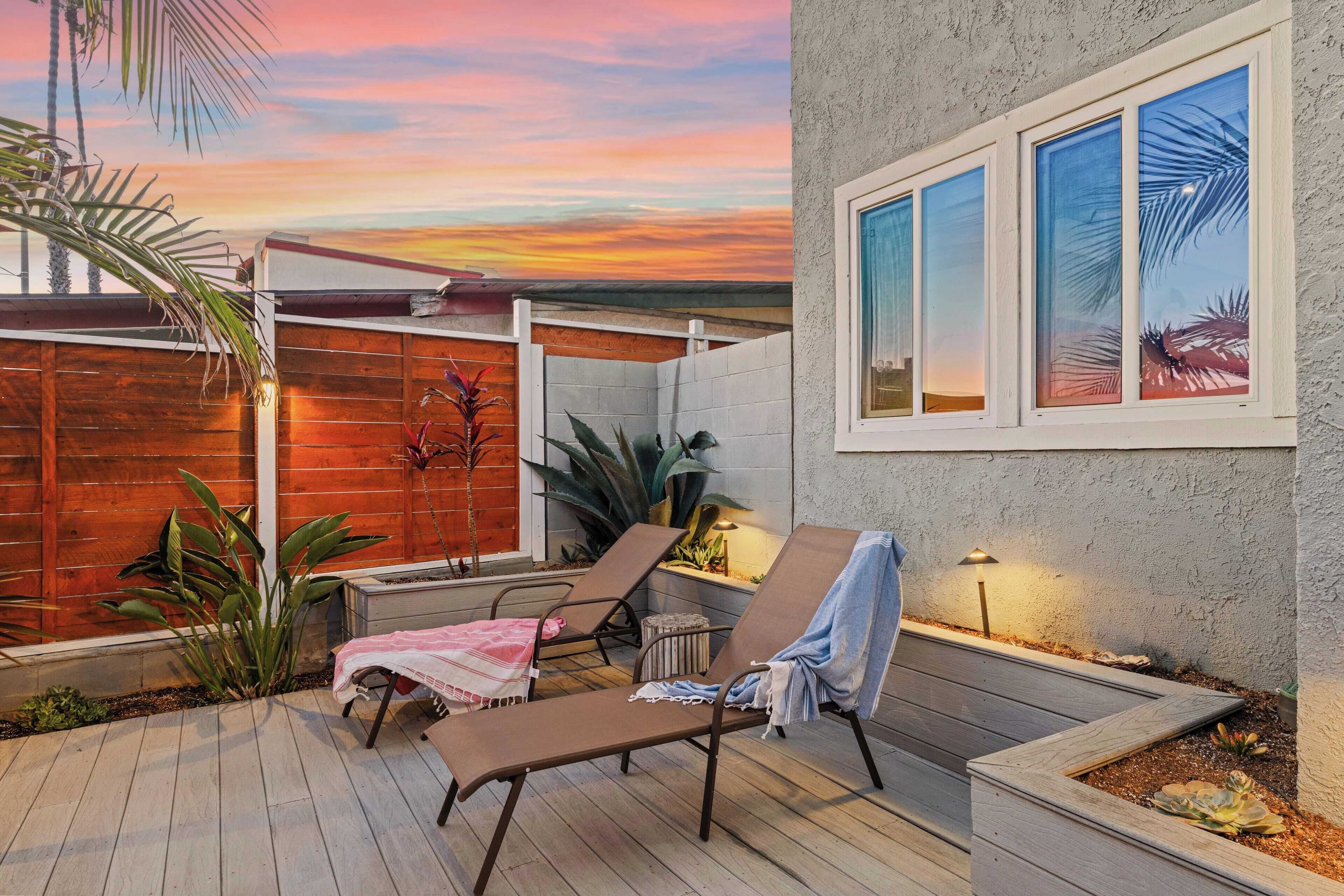 A patio with two lounge chairs, a small table, and a decorative plant.