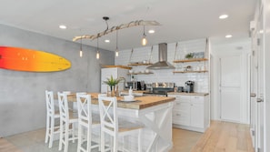 A modern kitchen with white cabinets, a wooden island, and pendant lighting.