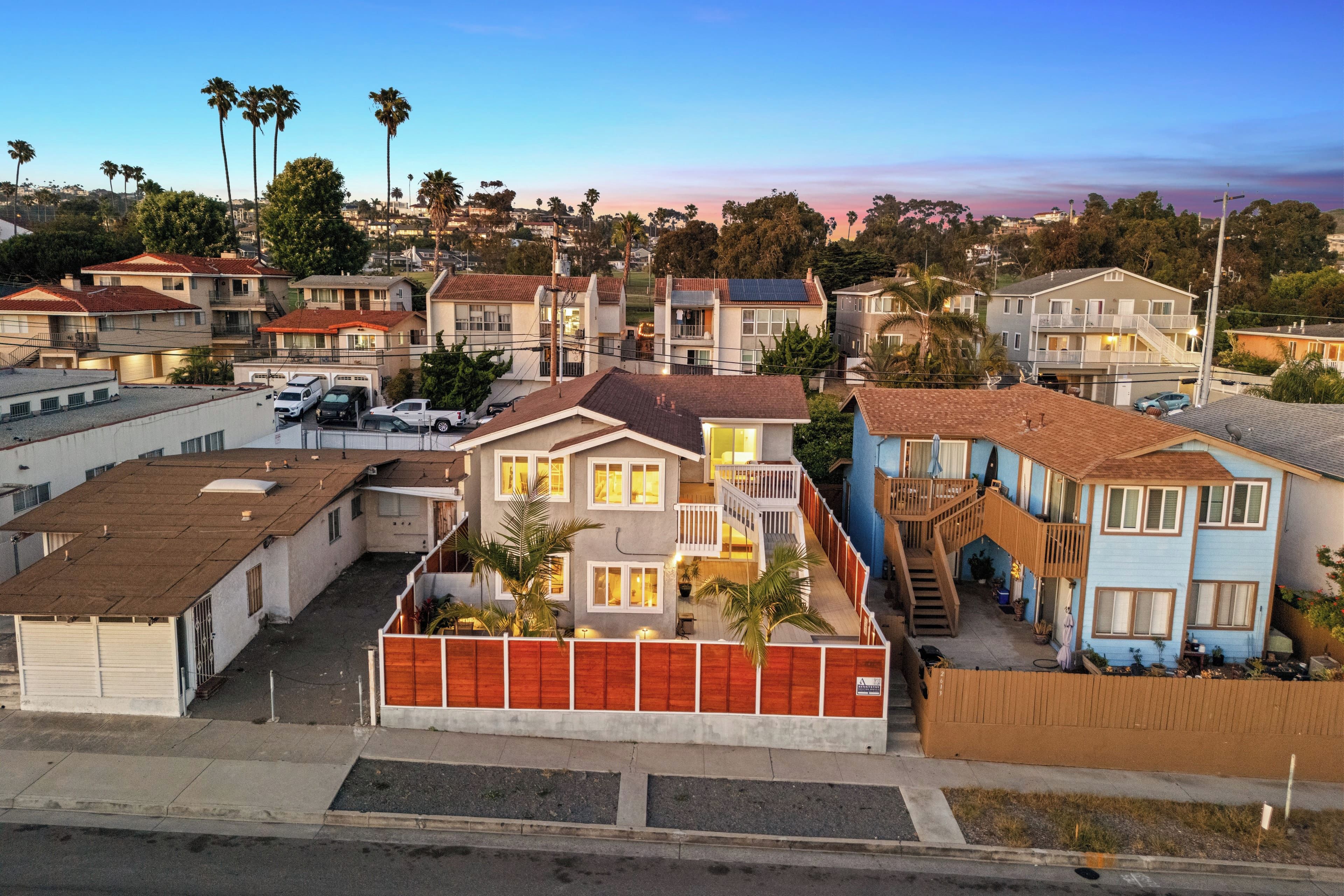 A residential area with multiple two-story houses, some with balconies, and a few with solar panels.