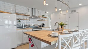 A modern kitchen with white cabinetry, a wooden island, and hanging pendant lights. - Walk to Trestles Beach Duplex w/ Ocean View El Camino Surfhouse by Avantstay (San Clemente)