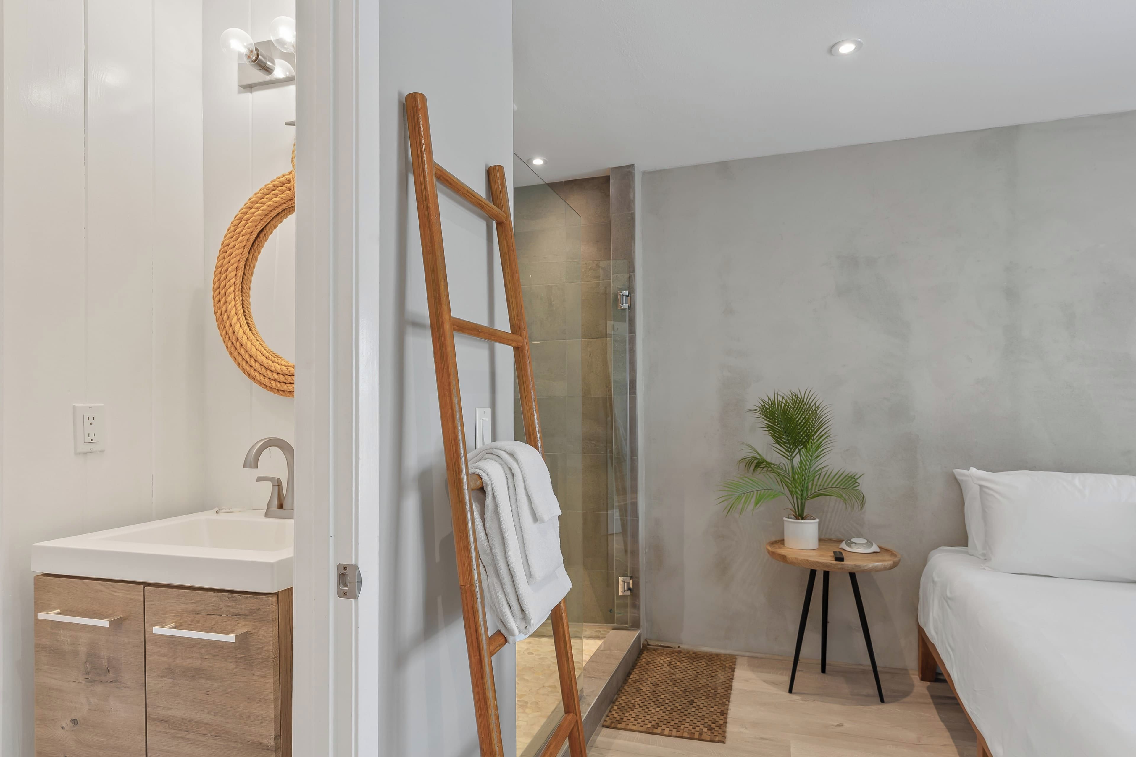 A modern bathroom with a wooden ladder, a sink, and a shower area.