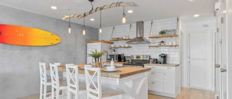 A modern kitchen with white cabinetry, a wooden island, and hanging pendant lights.