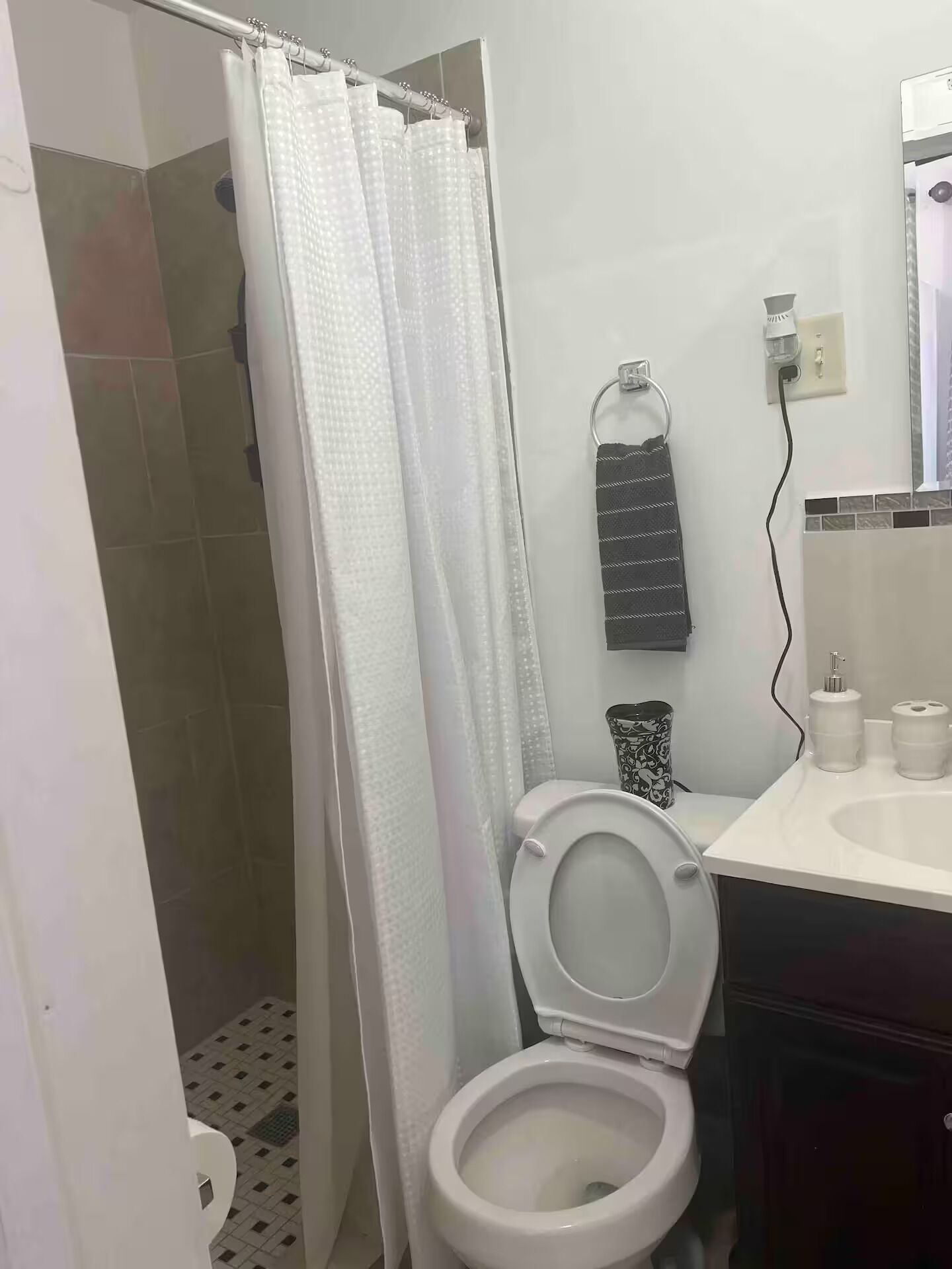 Un bagno con il water, una tenda doccia, un porta asciugamani e un lavandino con articoli da toilette.