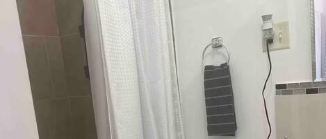 Un bagno con il water, una tenda doccia, un porta asciugamani e un lavandino con articoli da toilette.
