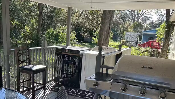 A covered outdoor patio with a grill, a round table, and two chairs. - Apartamento con buen confort (Jacksonville)
