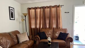 A living room with two brown leather sofas, a small black coffee table, and a floor lamp. - Apartamento con buen confort (Jacksonville)