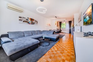 A modern living room with a sectional sofa, a coffee table, and a dining area with a table and chairs.
