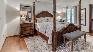 A four-poster bed with a wooden finish, a ceiling fan, and a nightstand with a lamp.