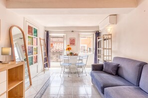 Ein Wohnzimmer mit Sofa, Couchtisch, Spiegel und einem Essbereich mit Stühlen und Tisch.